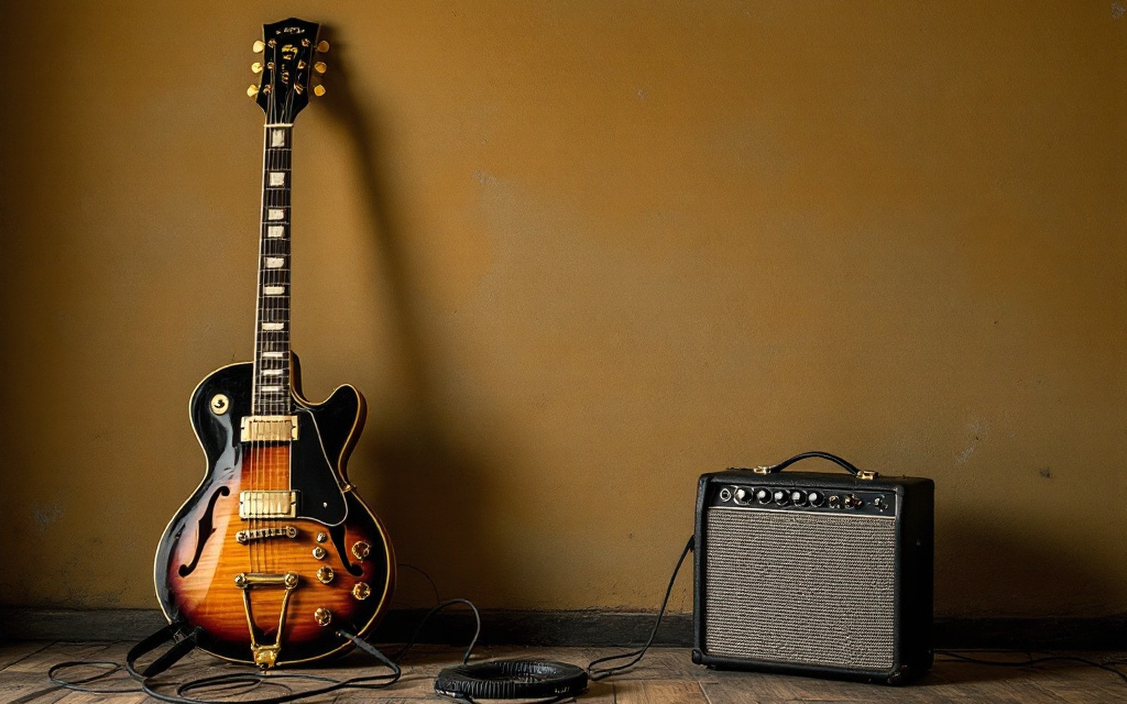 A guitar and small amplifier against a bare studio wall
