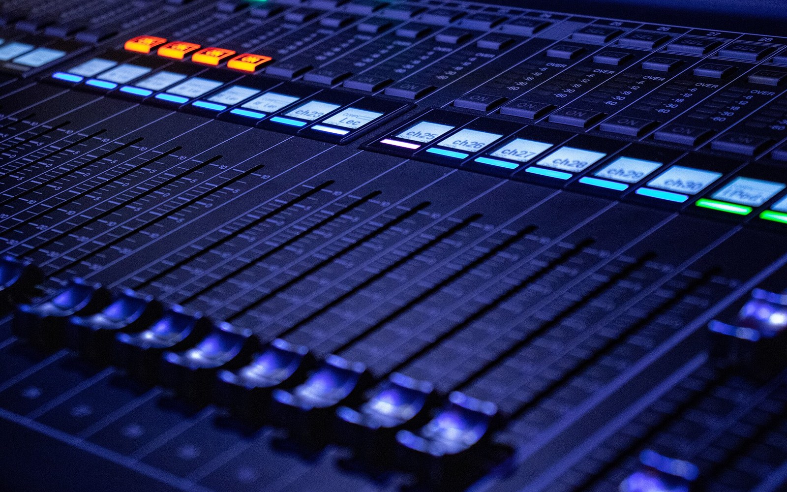 A recording console lit from above in a dim control room
